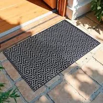 Tapete geométrico preto e branco na entrada de uma casa